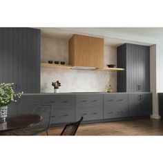 a kitchen with gray cabinets and wooden flooring is pictured in this image, there are flowers on the counter