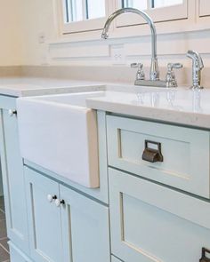 a kitchen sink with two faucets on the top and drawers below it, in front of a window