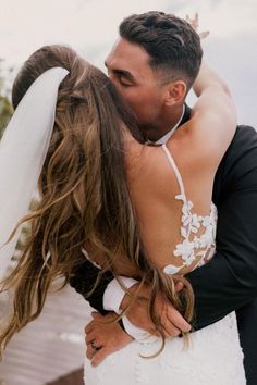 a bride and groom embracing each other on their wedding day in front of the ocean