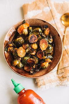 a bowl filled with brussel sprouts next to a bottle of syrup