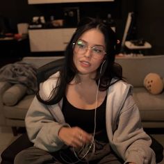 a woman wearing glasses and headphones sitting on a couch