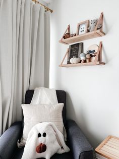 a chair with a stuffed animal on it in front of a wall shelf and window