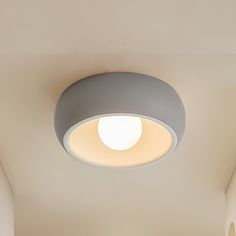 a bathroom with a toilet and a round light fixture on the ceiling in front of it