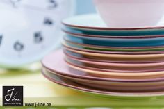 a stack of plates and cups sitting on top of each other in front of a clock