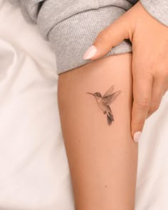 a woman's arm with a small hummingbird tattoo on the left side of her leg