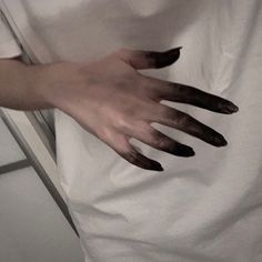 a person's hand on top of a white sheet with black claws sticking out of it