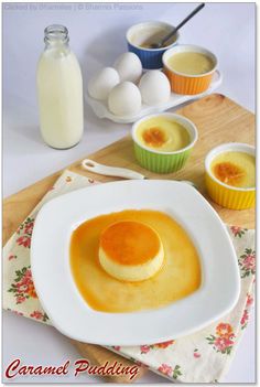 a plate with some pudding on it next to cups and spoons filled with eggs