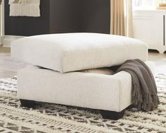 a white ottoman sitting on top of a rug