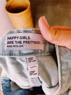 a person holding up a label that says, happy girls are the prettiest made with love