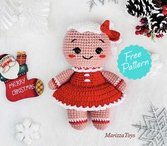 a crocheted teddy bear with a red dress next to a christmas ornament