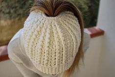 the back of a woman's head wearing a white knitted beanie hat