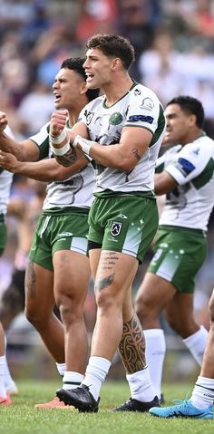 the rugby players are holding their hands together in celebration on the field at an outdoor stadium