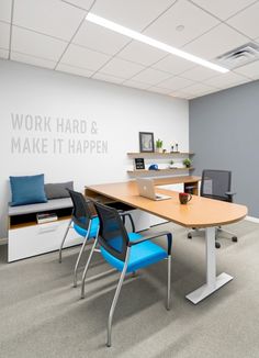 an office cubicle with blue chairs and a wooden table