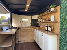 a kitchen area with shelves, cabinets and counter tops on the outside wall is covered in greenery