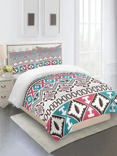 a bed with a colorful comforter and pillows on top of it in a room