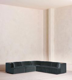 a black couch sitting on top of a hard wood floor next to a white wall