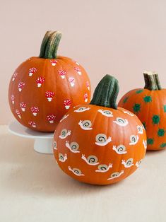 three painted pumpkins sitting on top of a white plate