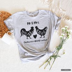 Bring a touch of whimsical romance to your wardrobe with this adorable Chicken Wedding Graphic T-Shirt! Featuring a charming illustration of a bride and groom chicken, this shirt is perfect for farm lovers and those who appreciate a unique and playful design. This Chicken Wedding T-shirt makes a fantastic gift for bachelorette parties, newlyweds, chicken enthusiasts, or anyone who loves a touch of rustic wedding charm. It's also a great choice for farm-themed weddings! Order your Chicken Wedding Graphic T-Shirt today and add a playful, romantic touch to your collection! Farm Wedding, Womens Farm Tshirt, Farmlife, Bridal Tshirt, Chicken Wedding, Chicken lovers, Womens Chicken Tee, Wedding Shirt FEATURES:    * Bella Canvas Tee    * Soft fabric    * Adult Unisex    * True Fit - Please see siz Wedding T-shirt With Custom Print And Short Sleeves, Custom Print Short Sleeve T-shirt For Wedding, Fitted Short Sleeve Tops For Anniversary, Short Sleeve Graphic Print Shirt For Wedding, Wedding Tshirts, Wedding Charm, Wedding Shirts, Bella Canvas Tees, Bachelorette Gifts