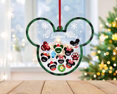 a mickey mouse ornament hanging on a table with a christmas tree in the background