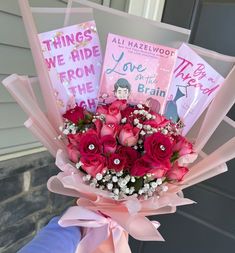 a bouquet of pink roses in front of a door with two books on the back