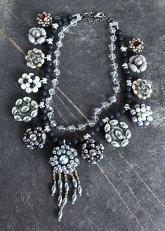 "This stunning silver / gray statement necklace is made with vintage clip on earrings. What a gorgeous formal piece this is, (thinking Mother of the Bride), a low cut evening or cocktail dress, or even a crisp white blouse with blue jeans. The silver/gray look is eye catching. The earrings are on bails in order to string them with black polished lava beads, and intermittent crystal rondels. The clear glass beaded chain above it is a beautiful complement to this head-turning necklace. Total possi Vintage Silver Bridal Necklace For Evening, Unique Silver Bridal Necklace, Unique Silver Bridal Necklace For Wedding, Elegant Gray Beaded Jewelry, Silver Bridal Necklace Costume Style, Silver Bridal Necklace Costume Jewelry, Glamorous Silver Beaded Bridal Necklace, Elegant Handmade Gray Jewelry, Handmade Elegant Gray Jewelry