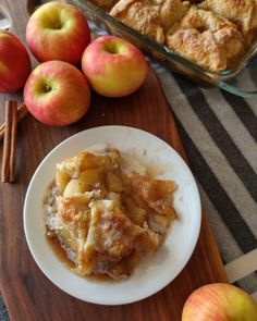 an apple cobbler is served on a plate with cinnamon sticks and apples in the background