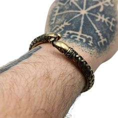 a man's arm with a tattoo on it and a snake bracelet attached to the wrist