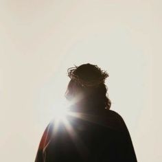 a person standing in the sun with their back turned to the camera and his hair pulled back