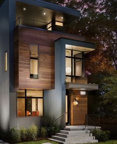 a modern house with stairs leading up to the front door and windows at night time