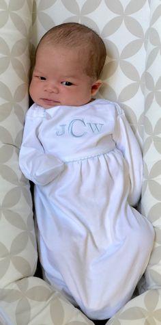 a baby wrapped in a blanket with the word jcc on it's chest