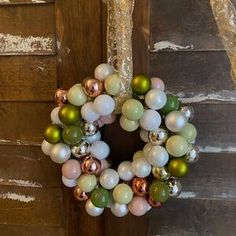 a christmas wreath hanging on the side of a wooden door with bauble decorations