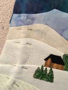 three quilts with trees and houses on them