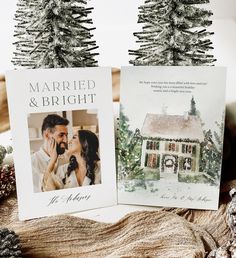 two christmas cards are sitting next to each other on a table with pine trees in the background