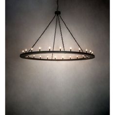 a circular chandelier with candles hanging from it's center, on a dark background