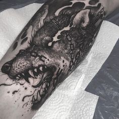 a black and white tattoo of a wolf on the leg