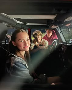 two people sitting in the passenger seat of a car, one smiling at the camera