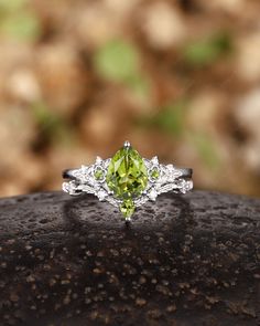 a close up of a ring with a green stone in the middle and diamonds on it