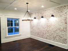 an empty room with wood floors and brick wall, lights on either side of the window