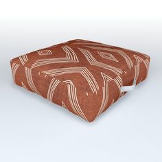 a brown and white square ottoman cover with an abstract design on the front, sitting on a plain surface