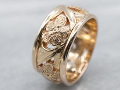 This piece dates to about the 1950s but still carries over a few hints of the preceding era. The craftsmanship is exquisite, with a wide, scrolling latticework at the center. Textured flowers are stationed at points along the way! This sits very low to the hand and will go well with a variety of styles of engagement pieces, or worn alone.Metal: 14K Yellow GoldWidth of Band: 9.4 mmHeight off Finger: 1.9 mmRing Size: 6.50Marks: “AIRES 14K” Stamped on the inside band Luxury Gold Bands With Intricate Design, Floral Wedding Band, Floral Wedding Bands, Vintage Wedding Ring, Wide Wedding Bands, Floral Filigree, Wedding Rings Vintage, Gold Pattern, Womens Wedding Bands