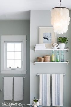 a bathroom with white towels hanging on the wall and shelves above it, along with other accessories