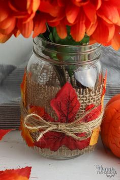 a glass jar filled with flowers on top of a table next to an orange pumpkin