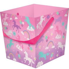 a pink gift bag with unicorns and rainbows all over the print on it