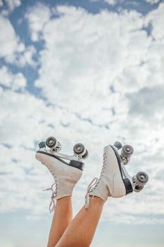 a woman's legs with roller skates on them and clouds in the background