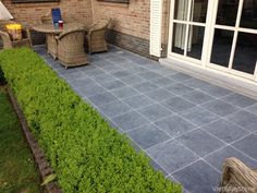 an outdoor patio with chairs and plants on it