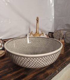 a white and black bowl sitting on top of a wooden table next to a bottle