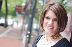 a close up of a person with a necklace on and a street in the background