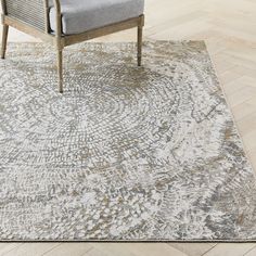 a gray chair sitting on top of a wooden floor next to a white and grey rug