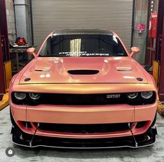 the front end of a pink car in a garage