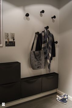 a coat rack with two coats hanging from it's hooks and shoes on the floor